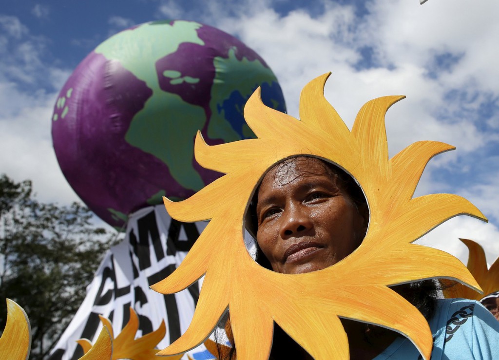 A Filipino environmental activist looks out from a "sun" cardboard cutout during a global protest action ahead COP21 summit in Quezon city