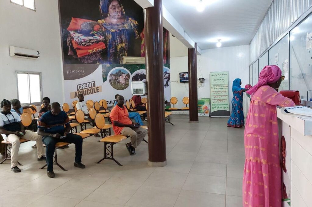 Persone in attesa e donne allo sportello di un istituto di microfinanza in Africa, partner dei progetti di microcredito internazionale di Banca Etica e Cresud.