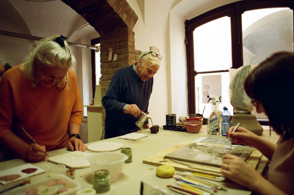 Libro fotografico La fatica non fa rumore: laboratorio artigianale in Val Susa con tre persone al lavoro su piastrelle e argilla, foto di Gabriele Scapola