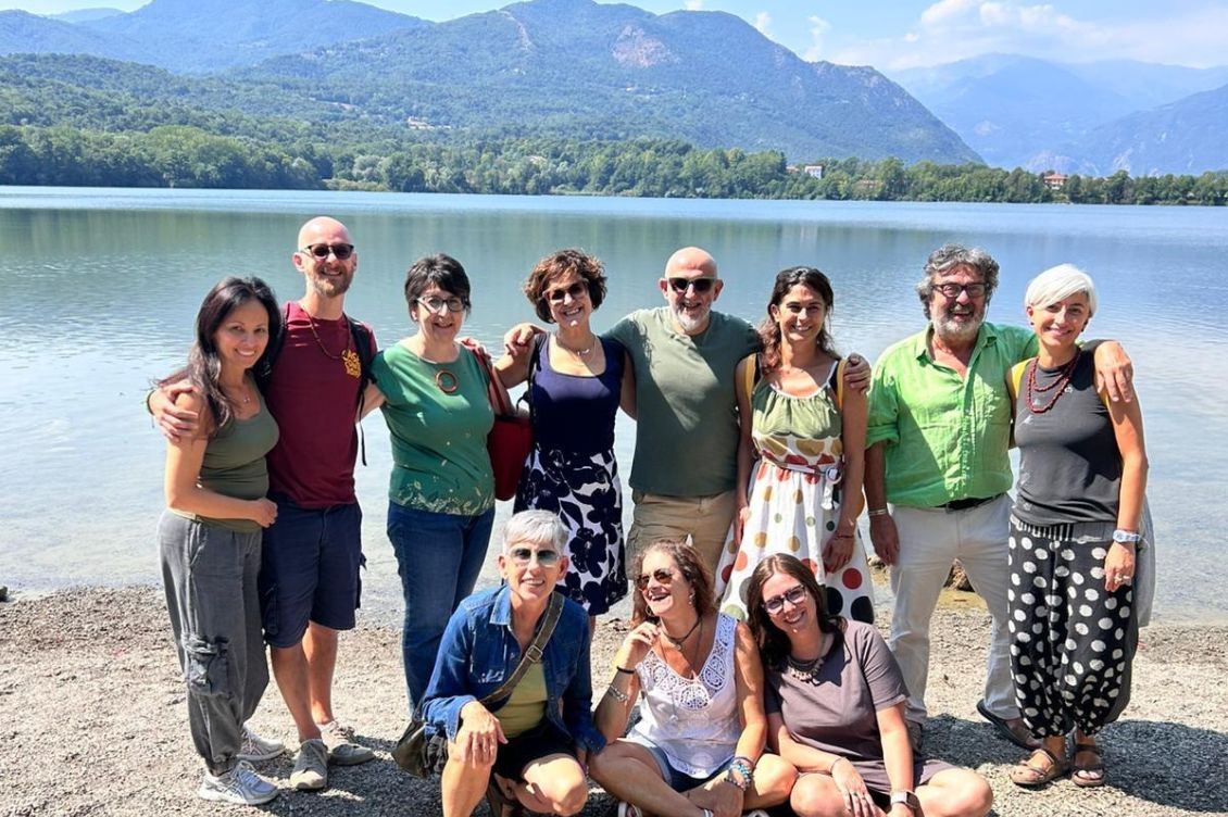 Alcune persone del team di Viaggi Solidali in gruppo sulla riva di un lago, simbolo del loro modo di fare turismo responsabile.