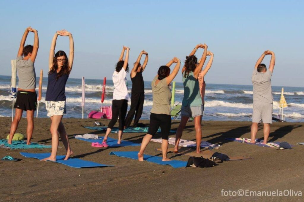 Partecipanti alle vacanze olistiche Nonsolomare durante una pratica di yoga in spiaggia