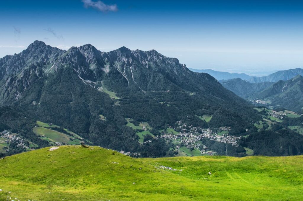Boschi italiani in area montana con paesi, prati e foreste lungo una valle alpina